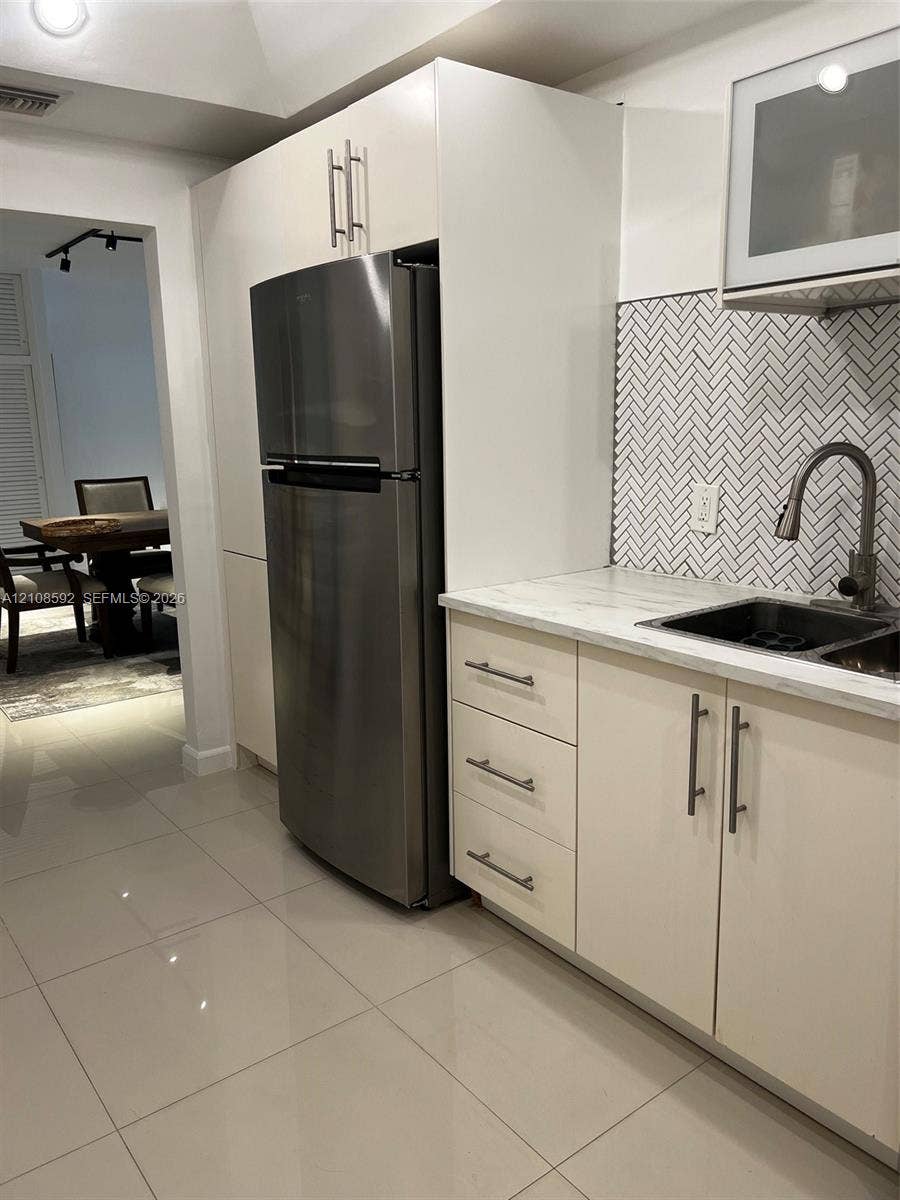 10185 Collins Avenue, #515, Bal Harbour, Bal Harbour, FL 33154 Kitchen featuring flat-panel cabinetry, stainless steel refrigerator, stone-surface countertop, herringbone tile backsplash, and undermount dual-basin sink with high-arc faucet