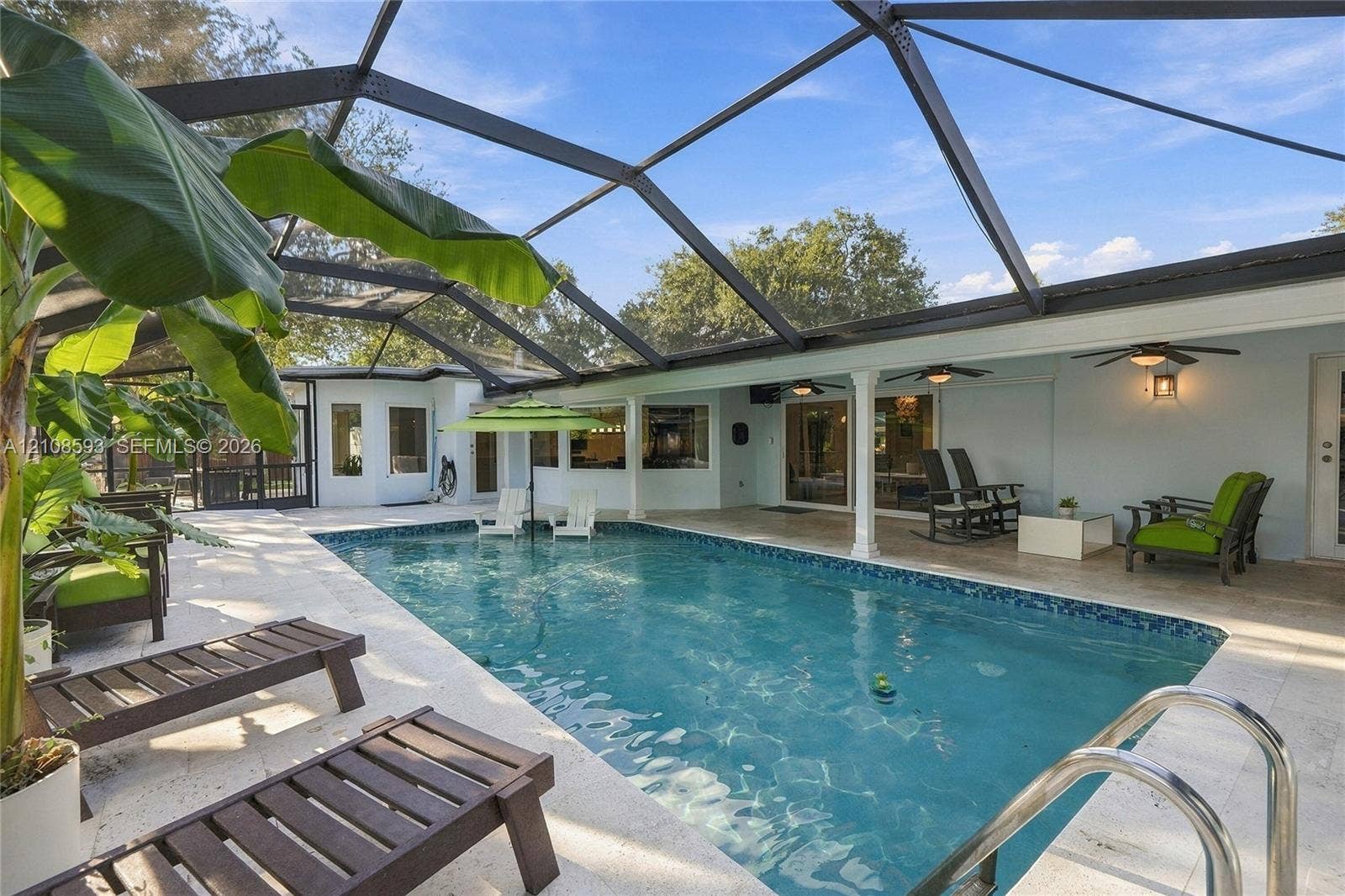 8230 SW 151st Street, Palmetto Bay, FL 33158 Screen-enclosed swimming pool featuring a tiled waterline, stone-finish decking, and recessed ceiling fans