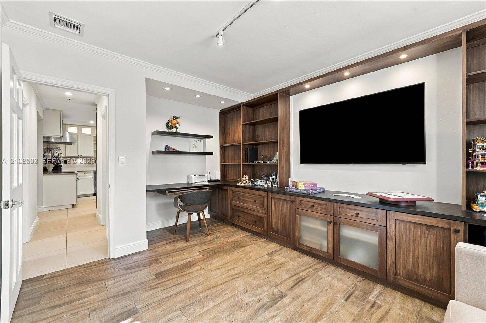 8230 SW 151st Street, Palmetto Bay, FL 33158 Custom built-in wood cabinetry with integrated shelving and drawers, dark countertop, recessed lighting, and wood-finish flooring