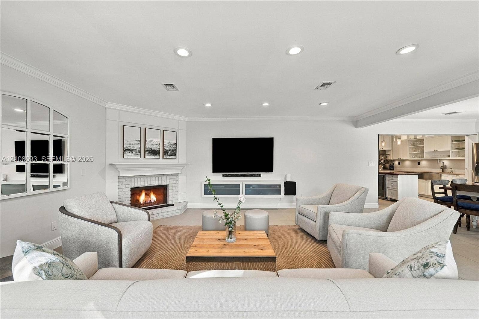 8230 SW 151st Street, Palmetto Bay, FL 33158 Living area featuring a painted brick corner fireplace with a mantel, recessed ceiling lighting, crown molding, and built-in cabinetry
