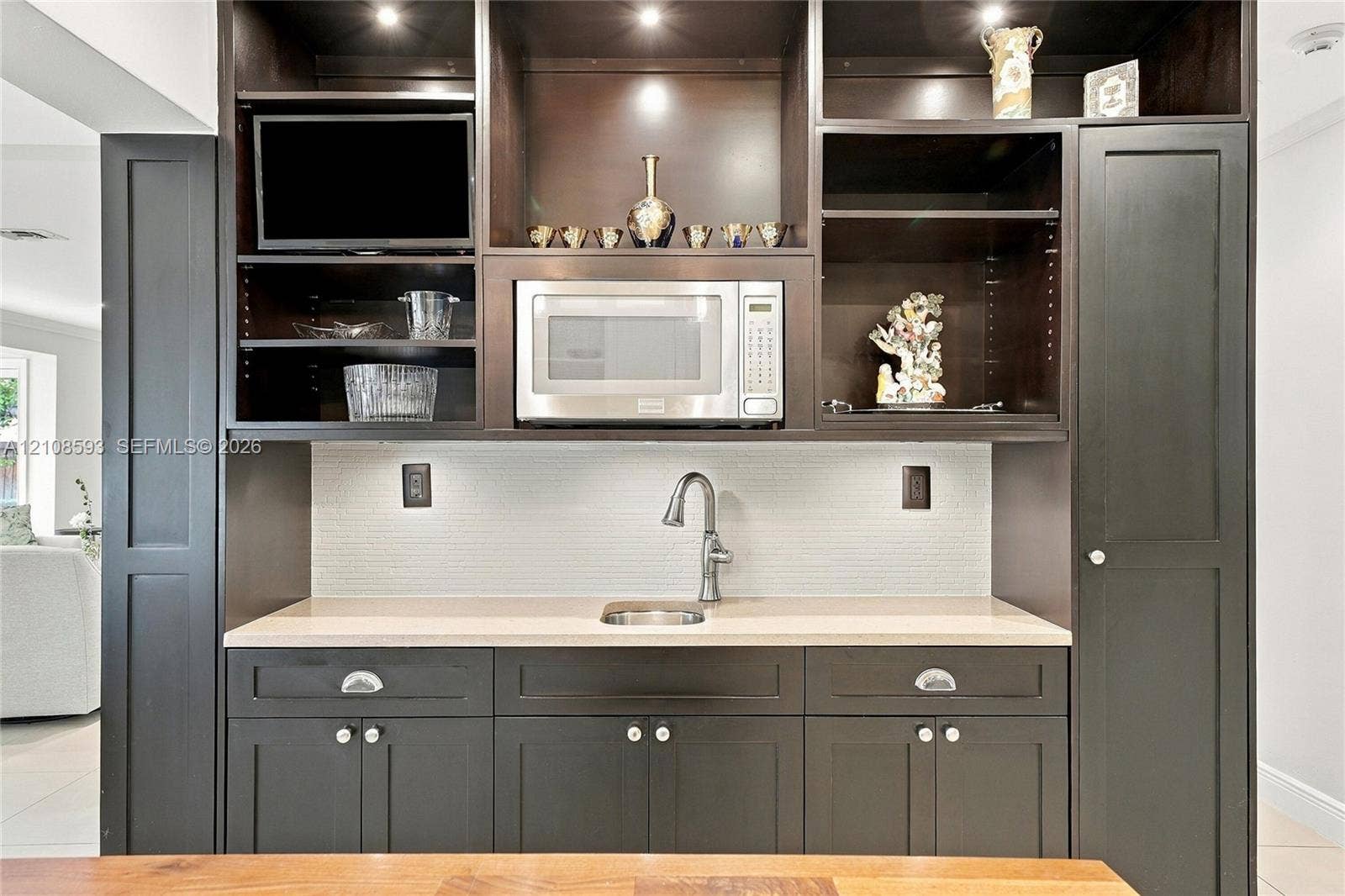 8230 SW 151st Street, Palmetto Bay, FL 33158 Built-in cabinetry featuring dark finish, recessed task lighting, integrated microwave, stone-finish countertop, and undermount stainless steel sink with gooseneck faucet