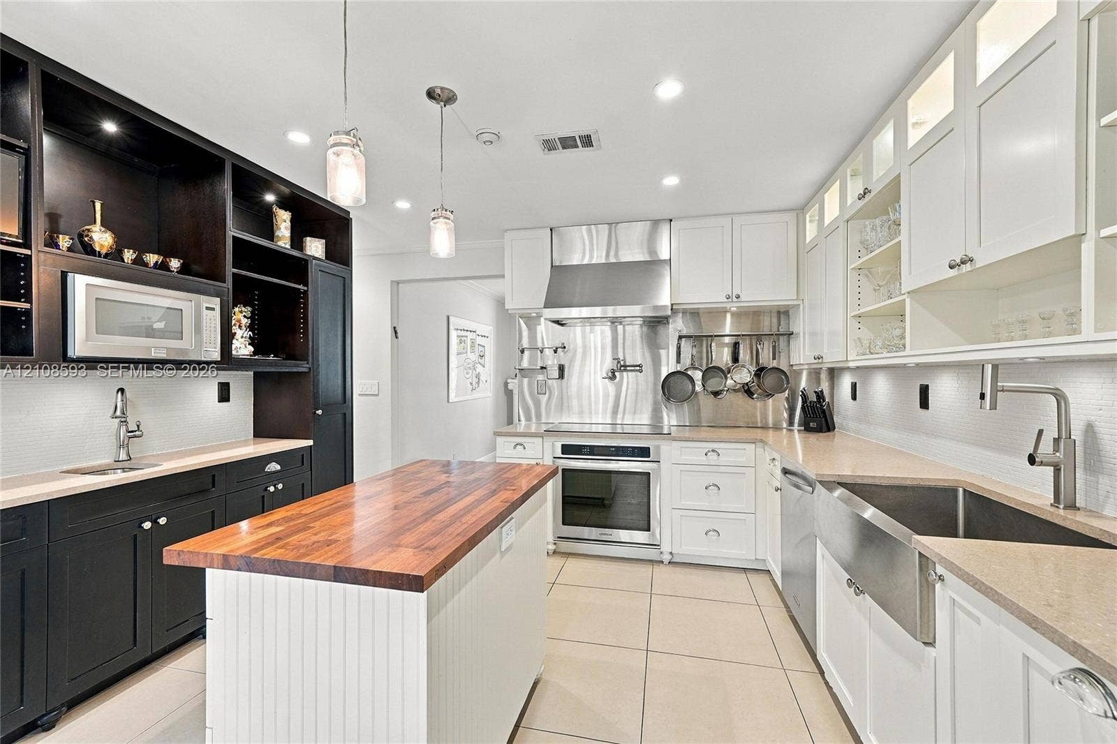8230 SW 151st Street, Palmetto Bay, FL 33158 Kitchen featuring high-contrast cabinetry, butcher block island countertop, professional-grade stainless steel range hood, apron-front sink, and tiled flooring