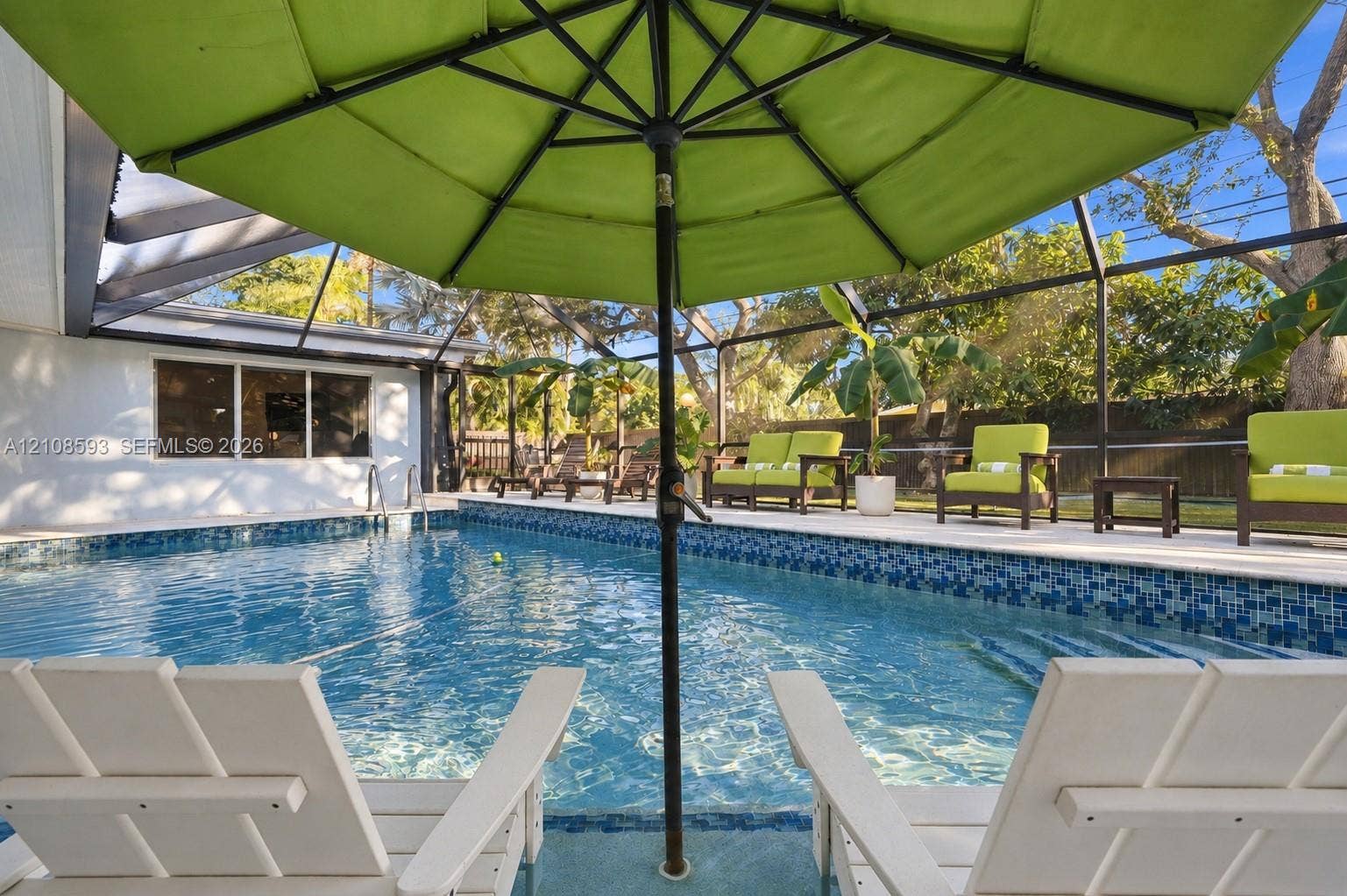8230 SW 151st Street, Palmetto Bay, FL 33158 Screened-in patio area featuring a swimming pool with blue mosaic tile perimeter and concrete pool deck