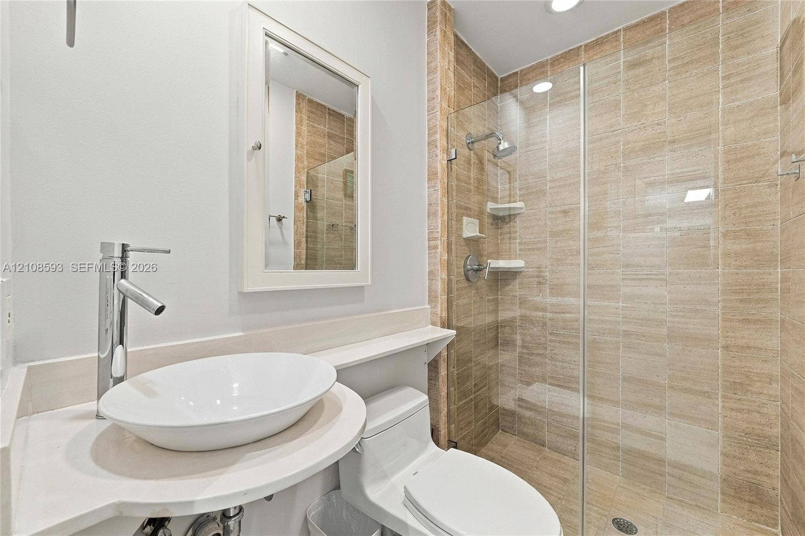 8230 SW 151st Street, Palmetto Bay, FL 33158 Bathroom featuring a white oval vessel sink, chrome high-arc faucet, solid surface countertop, walk-in shower with floor-to-ceiling tile, and frameless glass door