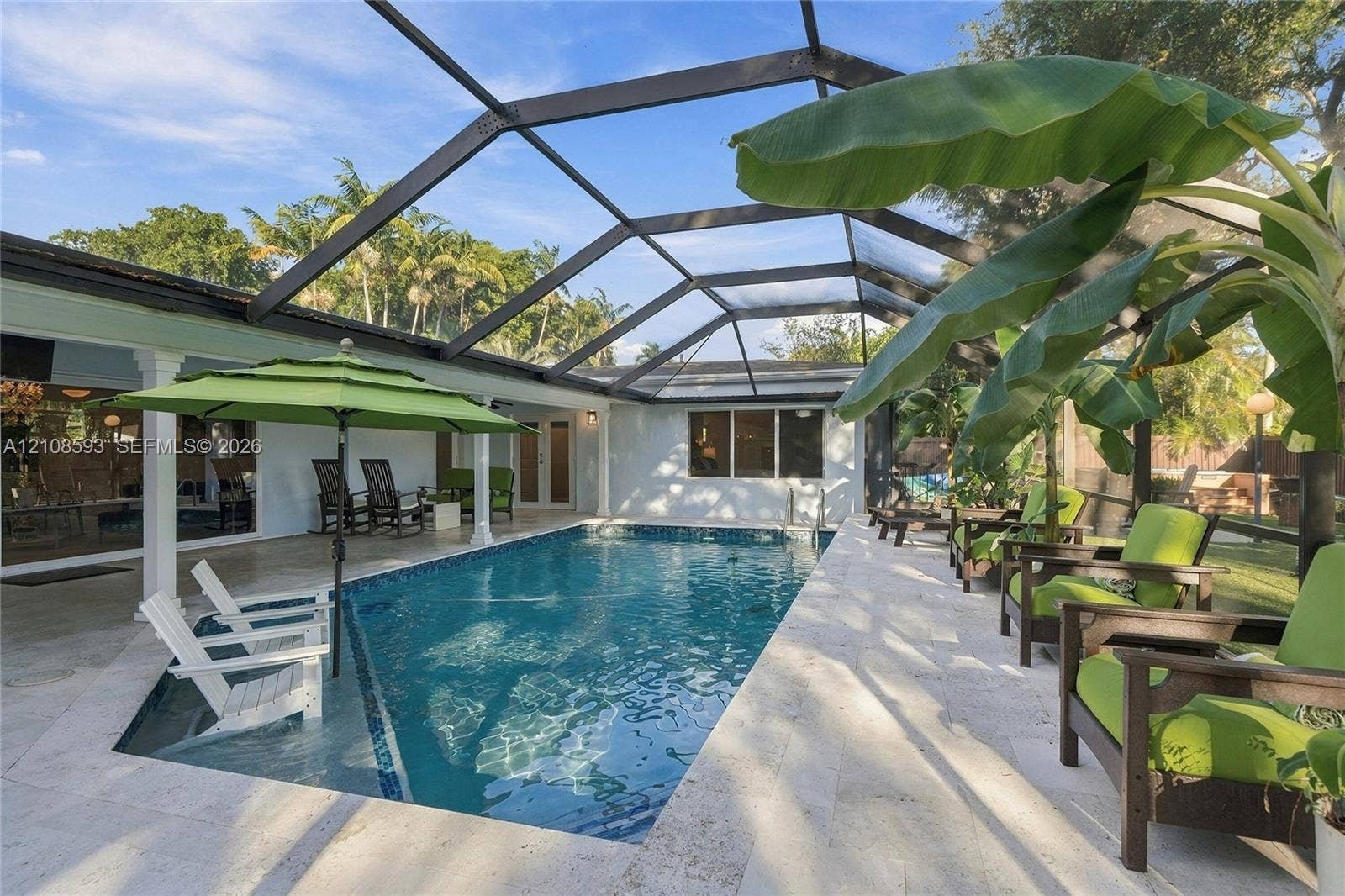 8230 SW 151st Street, Palmetto Bay, FL 33158 Screen-enclosed swimming pool featuring a Baja shelf, natural stone patio, and covered patio area