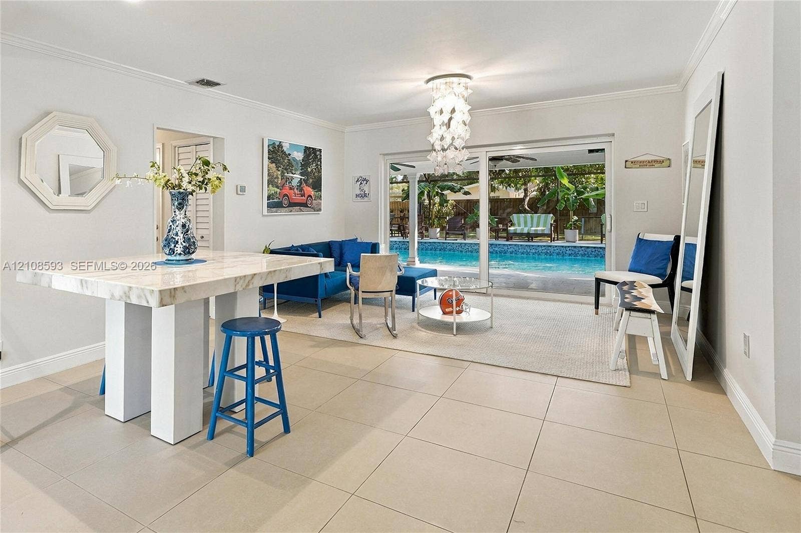8230 SW 151st Street, Palmetto Bay, FL 33158 Large-format tile flooring, decorative multi-tiered light fixture, and sliding glass doors opening to an exterior swimming pool