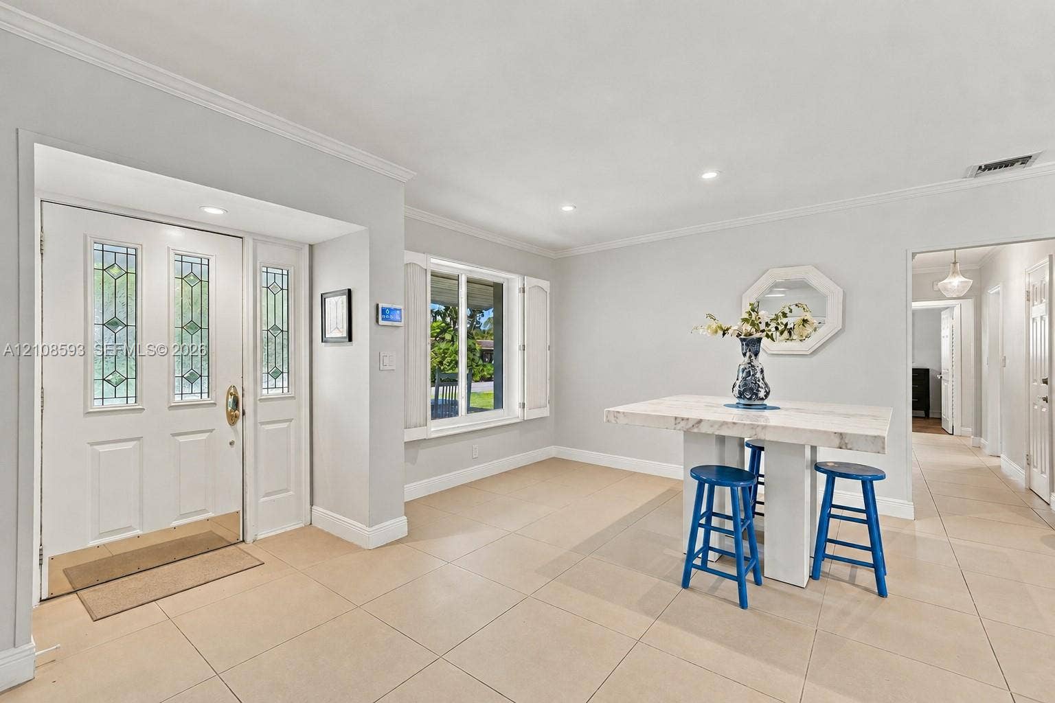 8230 SW 151st Street, Palmetto Bay, FL 33158 Entryway featuring a white door with decorative glass panels, neutral tile flooring, recessed lighting, crown molding, and window shutters