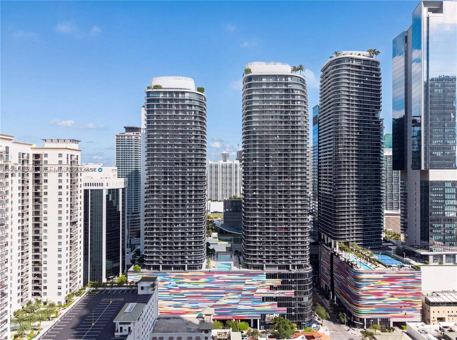 45 SW 9th Street, #2206, Miami, FL 33130 High-rise glass facade residential towers featuring expansive balconies, roof-level outdoor recreation decks, and a colorful multi-story architectural podium