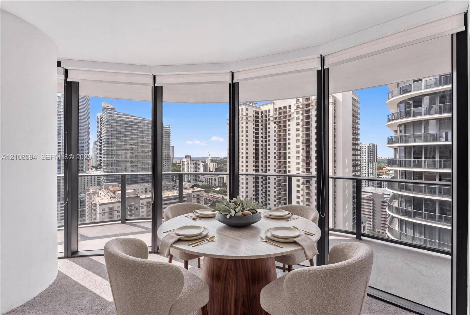 45 SW 9th Street, #2206, Miami, FL 33130 Curved floor-to-ceiling windows, wrap-around private balcony with metal railing, and neutral wall-to-wall carpeting