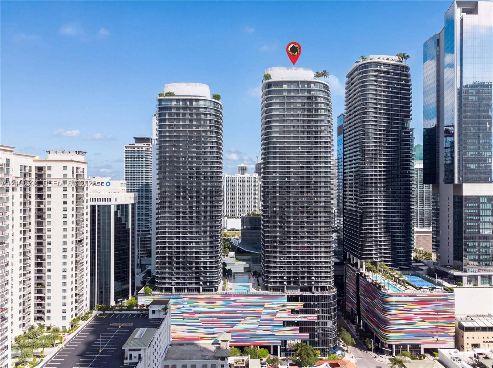 45 SW 9th Street, #2206, Miami, FL 33130 High-rise tower featuring a glass facade, multiple balconies, a rooftop terrace, and architectural detailing with a multi-colored exterior finish
