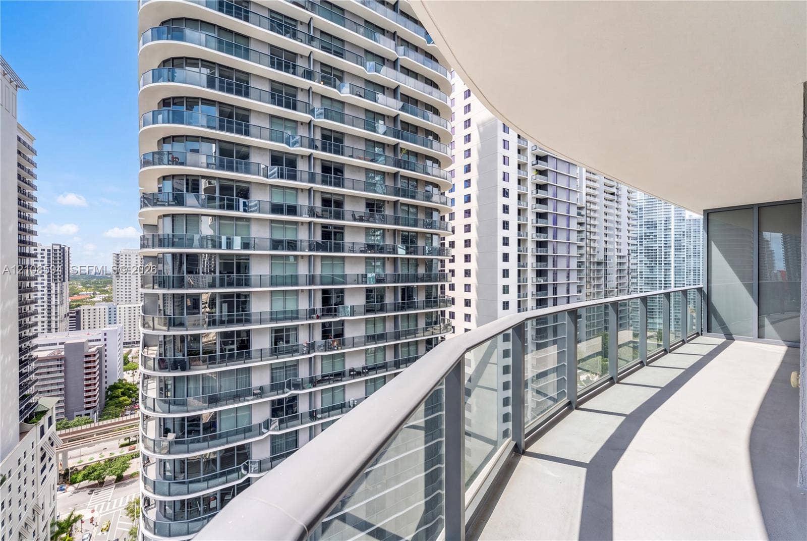 45 SW 9th Street, #2206, Miami, FL 33130 Covered outdoor balcony featuring a curved structural design, concrete flooring, and metal railing with glass panels
