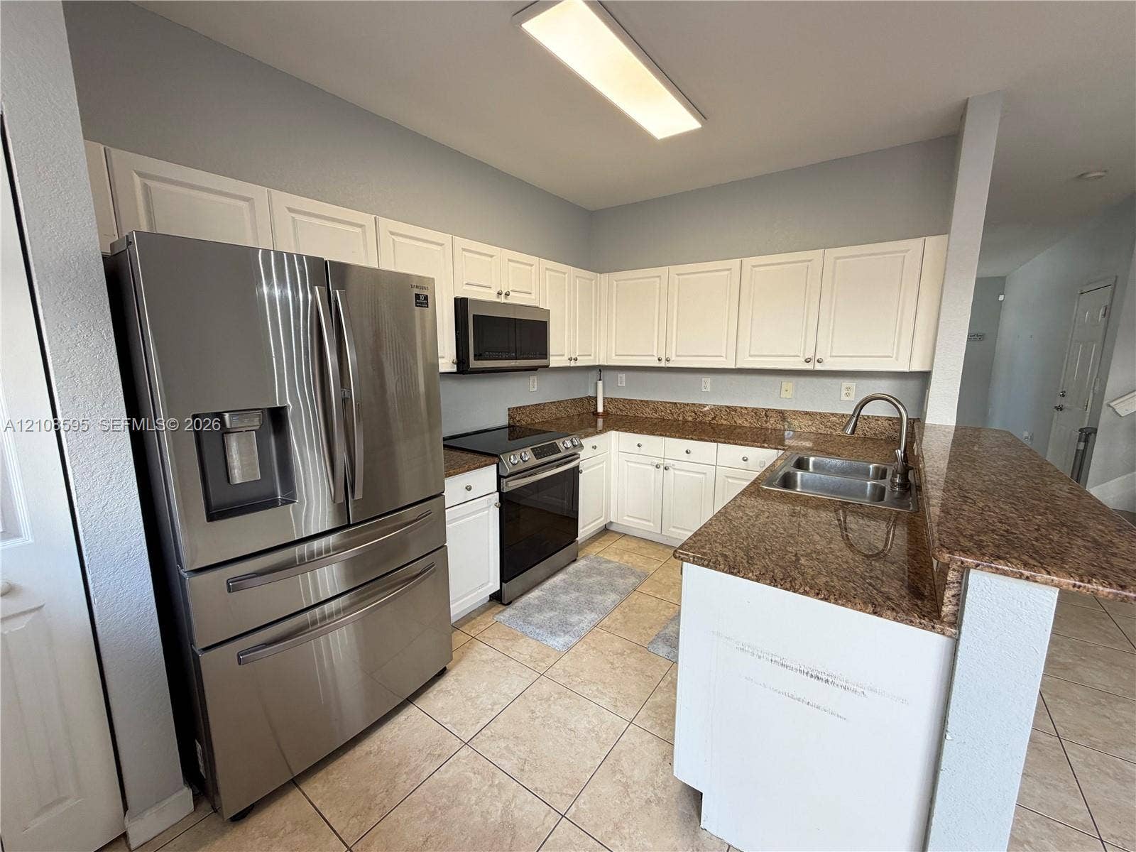 12989 SW 135th Terrace, #0, Miami, Miami, FL 33186 Kitchen featuring white cabinetry, stone-finish countertops, tile flooring, stainless steel French-door refrigerator, and an integrated stainless steel sink with a high-arch faucet