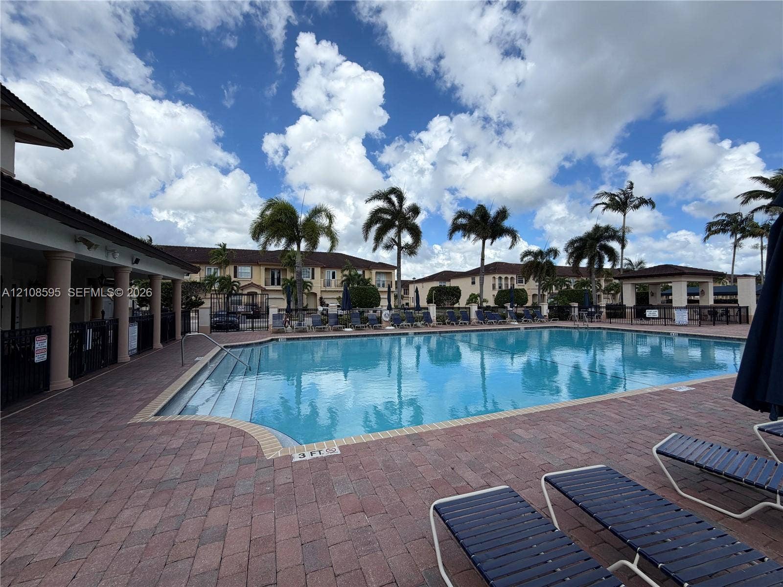 12989 SW 135th Terrace, #0, Miami, Miami, FL 33186 Community swimming pool featuring a brick paver deck, covered veranda with structural columns, and mature palm trees