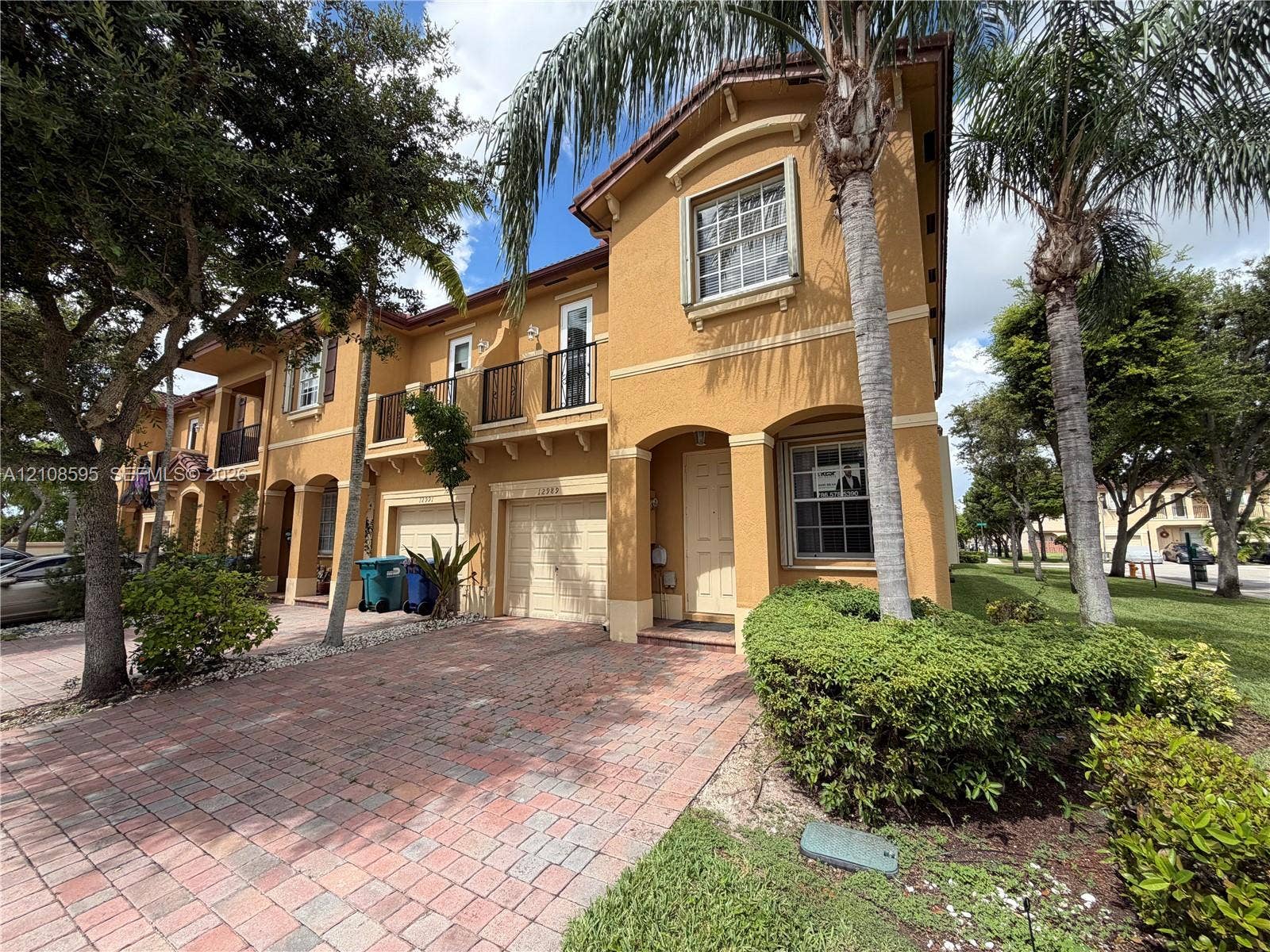 12989 SW 135th Terrace, #0, Miami, Miami, FL 33186 Stucco exterior featuring arched entryways, a paver driveway, an attached garage, and second-story metal-railing balconies