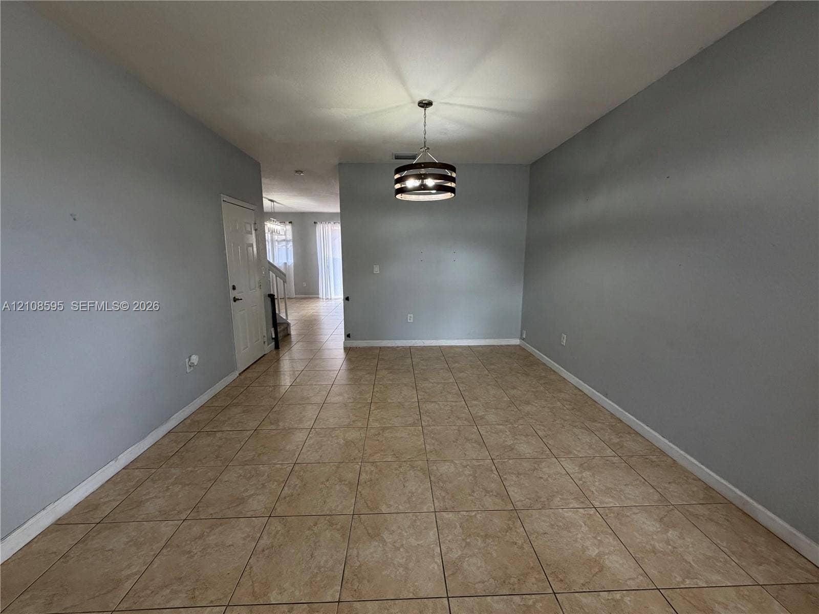 12989 SW 135th Terrace, #0, Miami, Miami, FL 33186 Neutral-toned interior featuring ceramic tile flooring, a drum-style pendant light fixture, and a multi-panel door