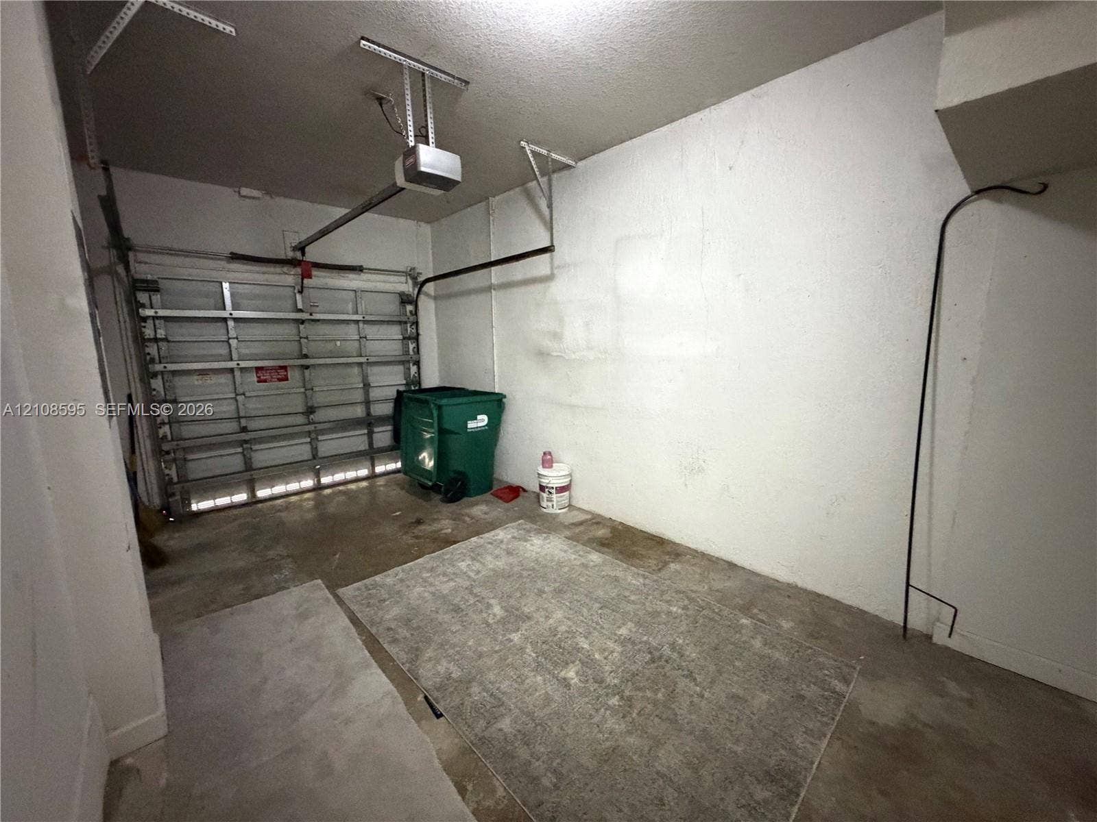 12989 SW 135th Terrace, #0, Miami, Miami, FL 33186 Enclosed garage space featuring a metal sectional door and automated overhead door opener