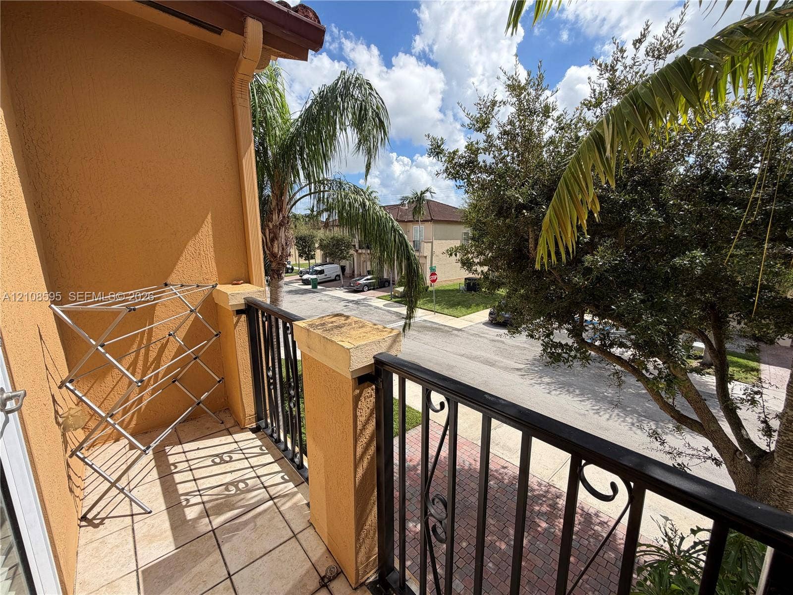12989 SW 135th Terrace, #0, Miami, Miami, FL 33186 Covered balcony featuring tile flooring, stucco walls, and decorative metal railings with stone-capped pillars