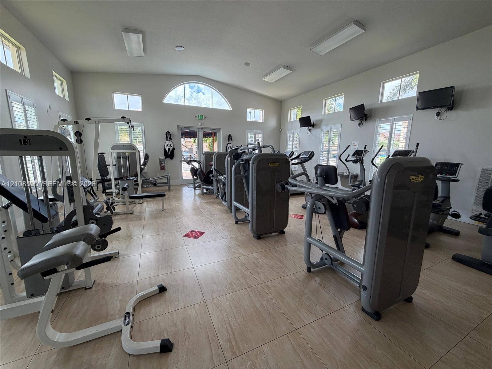 12989 SW 135th Terrace, #0, Miami, Miami, FL 33186 Fitness center featuring large-format tile flooring, vaulted ceilings with recessed lighting, and multiple windows including an arched architectural accent