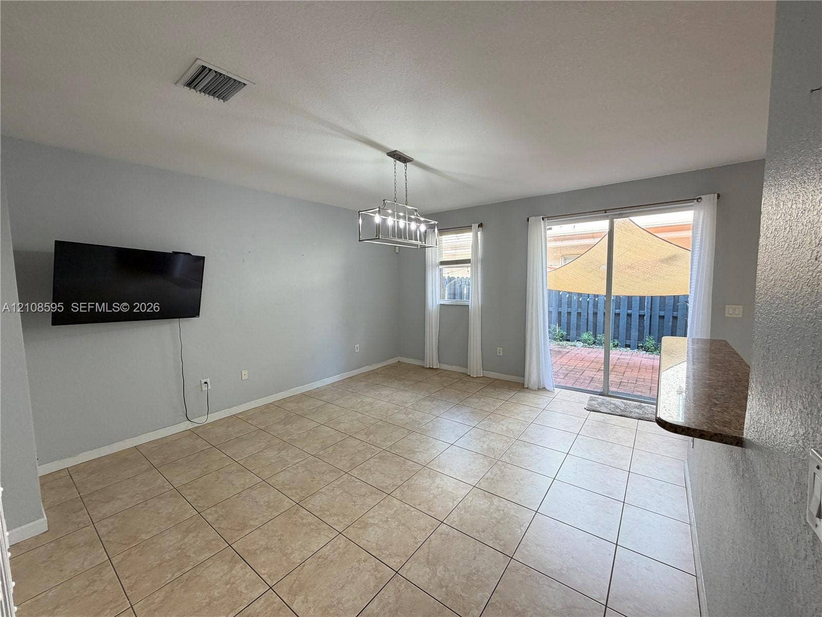 12989 SW 135th Terrace, #0, Miami, Miami, FL 33186 Ceramic tile flooring, industrial-style multi-light chandelier, sliding glass door, and a built-in stone-finish counter