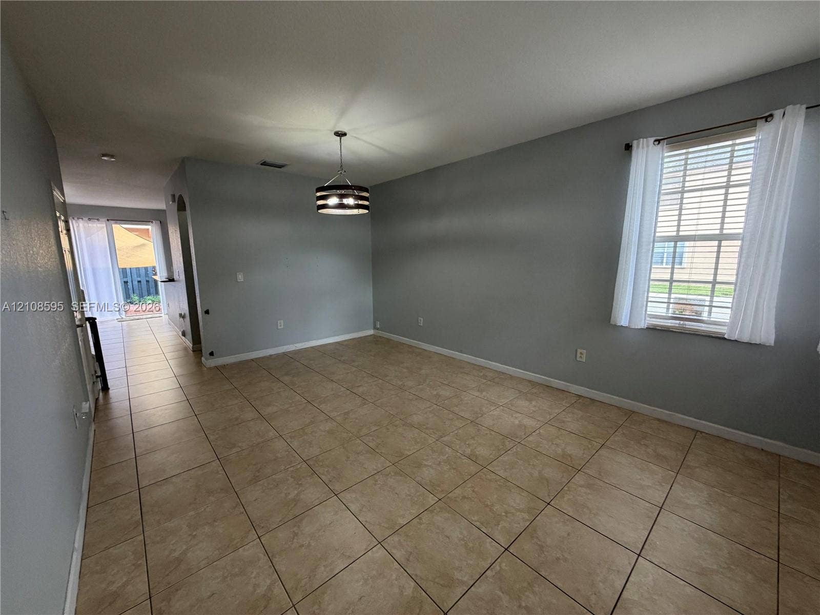 12989 SW 135th Terrace, #0, Miami, Miami, FL 33186 Open-concept room featuring neutral-toned tile flooring, recessed lighting, a modern drum-style pendant light, and a double-hung window