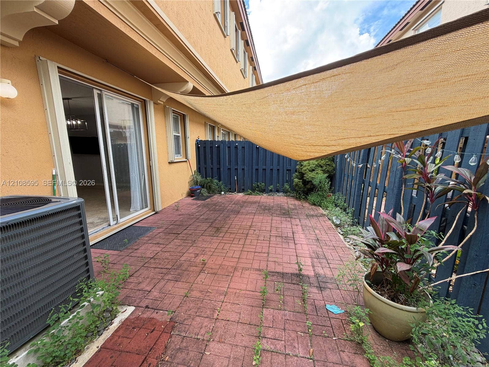 12989 SW 135th Terrace, #0, Miami, Miami, FL 33186 Private patio featuring red brick paving, a retractable overhead shade canopy, and perimeter wood fencing