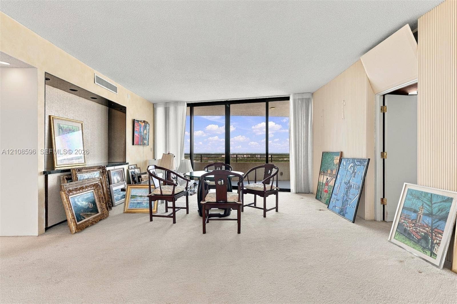 Living area featuring floor-to-ceiling glass sliding doors, a built-in recessed wall niche with integrated lighting, and carpeted flooring