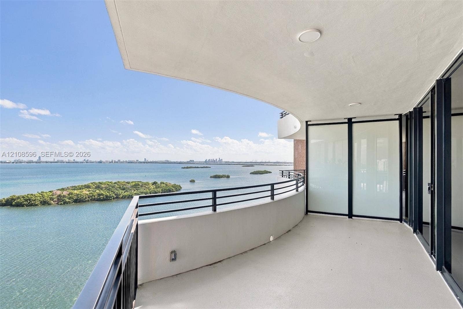 Curved balcony featuring a concrete surface, metal railing, frosted glass partition, and recessed ceiling lighting