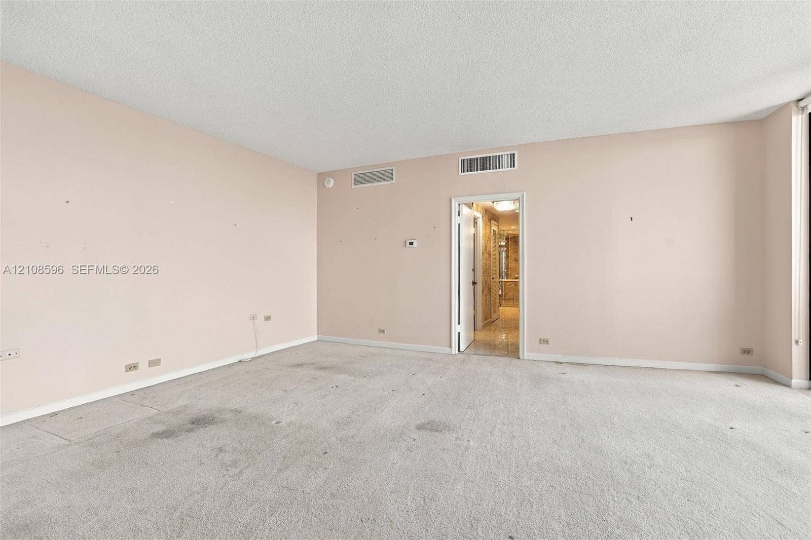 Expansive interior room featuring neutral wall finishes, plush carpeting, and recessed ceiling HVAC registers