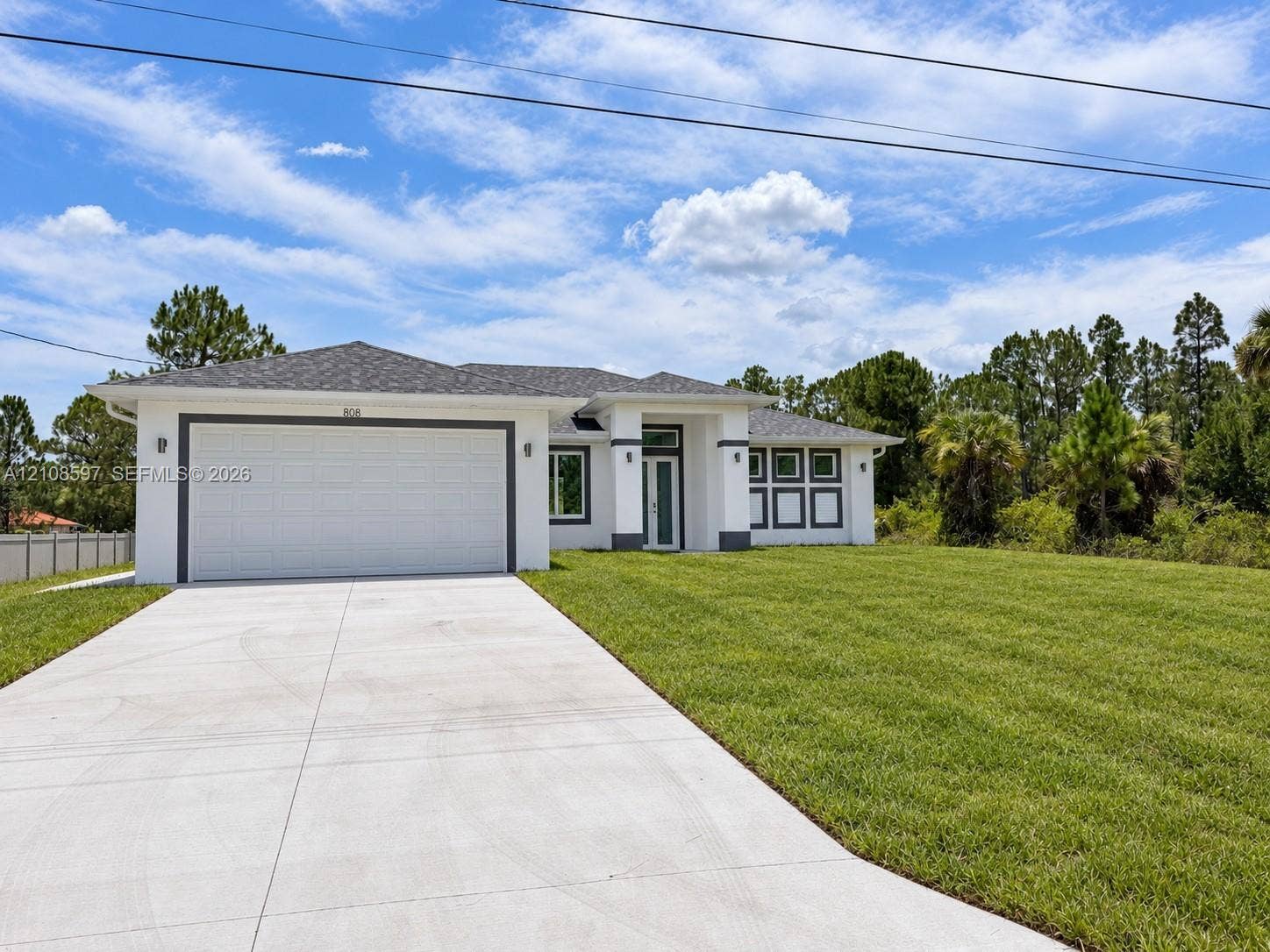 808 Congress Avenue, Lehigh Acres, FL 33972 Single-story exterior featuring white stucco siding, a grey shingled hip roof, a concrete driveway, and an attached two-car garage
