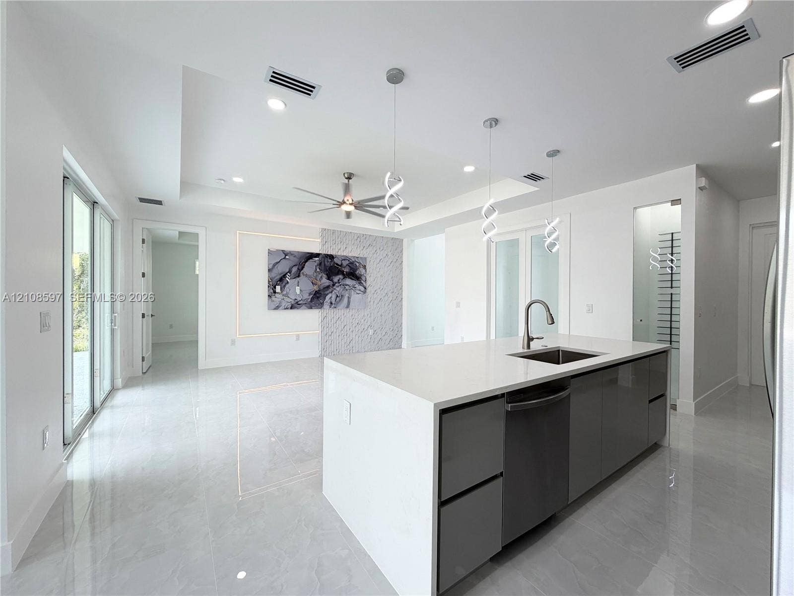 Kitchen island featuring a stone-composite countertop, undermount sink, and high-gloss cabinetry