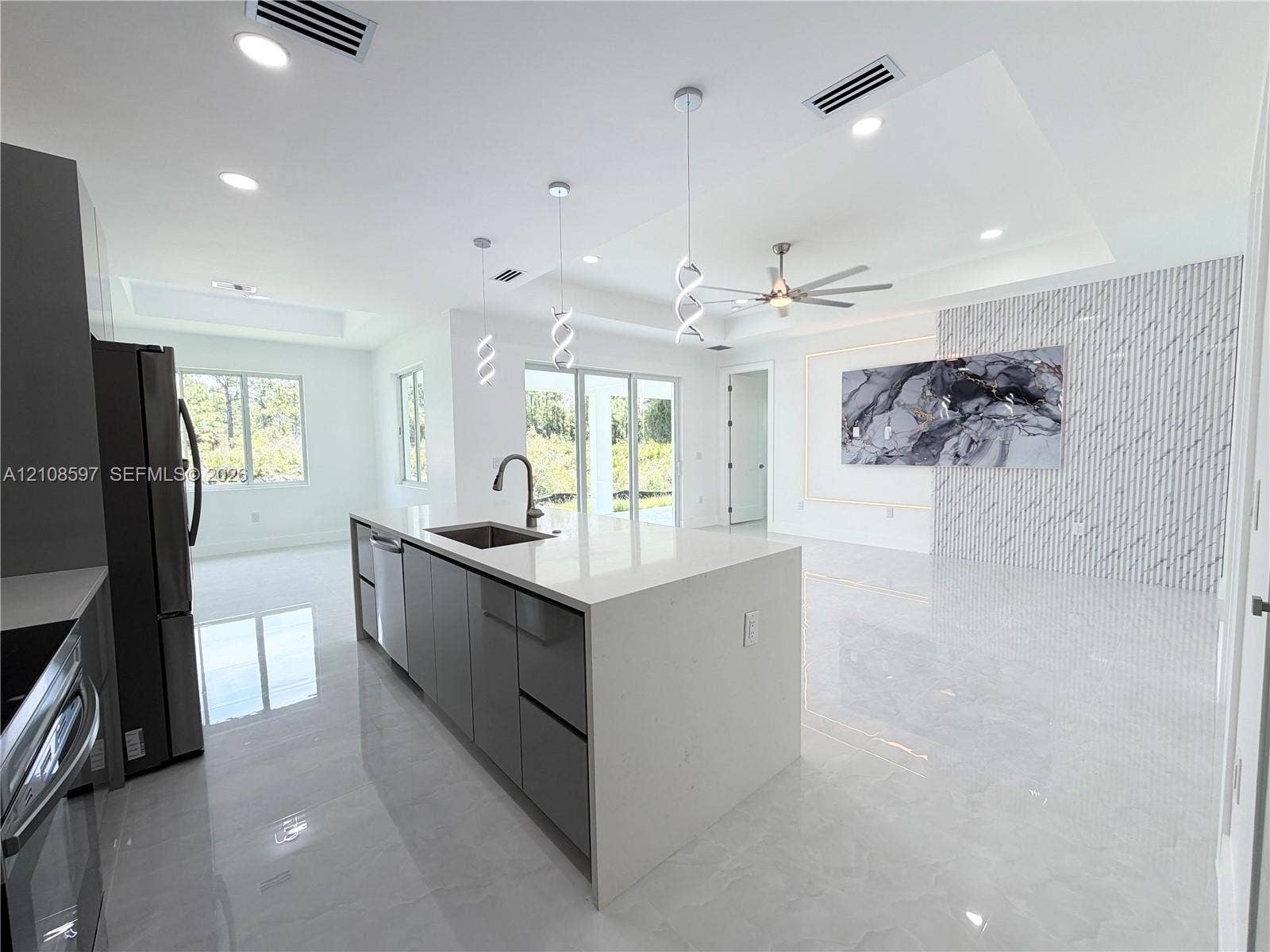 808 Congress Avenue, Lehigh Acres, FL 33972 Open-concept kitchen featuring an oversized island with quartz countertops, custom cabinetry, recessed lighting, stone-finish wall cladding, and oversized light-colored floor tiles