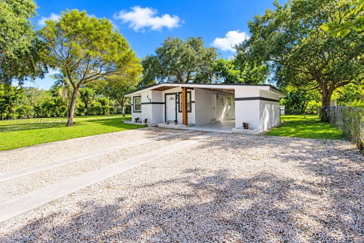 Single-story residence featuring a mid-century modern aesthetic, stucco exterior, integrated carport, concrete driveway, and mature landscaping