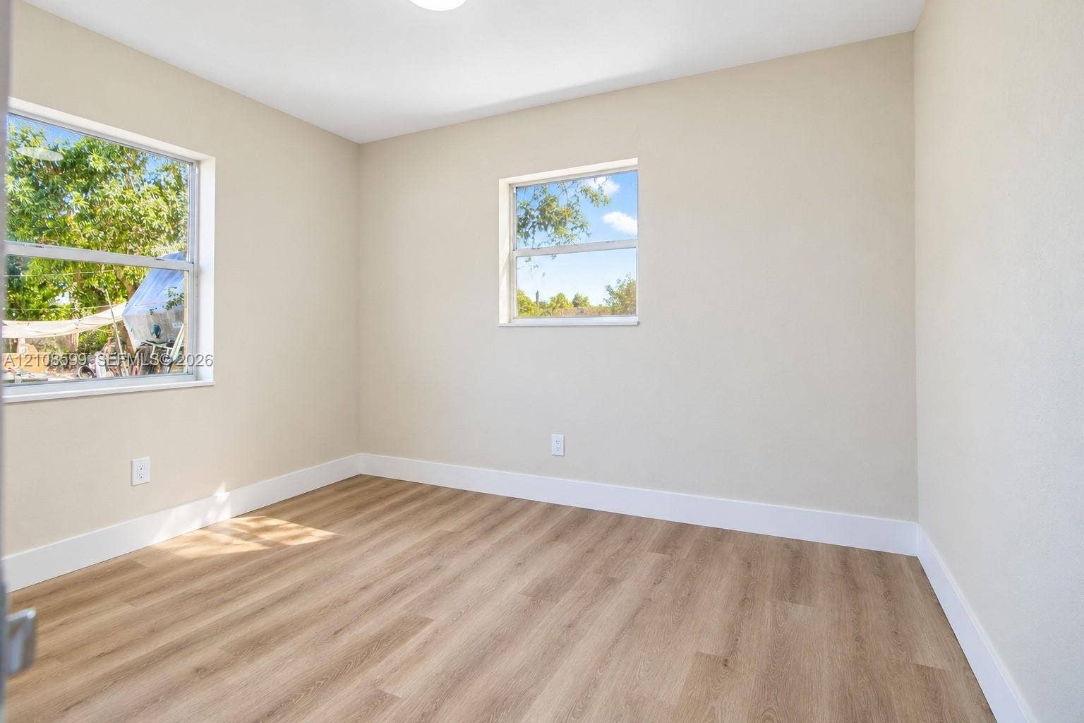 Interior space featuring neutral-toned walls, wood-finish flooring, and two dual-pane windows