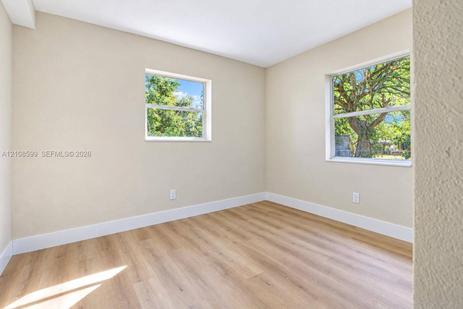 Neutral-toned interior space featuring wood-finish flooring, dual windows, and smooth wall finishes