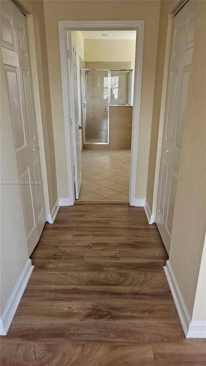 24041 SW 114th Place, Homestead, FL 33032 Wood-finish flooring, two sets of paneled closet doors, and tiled flooring leading to a glass-enclosed shower