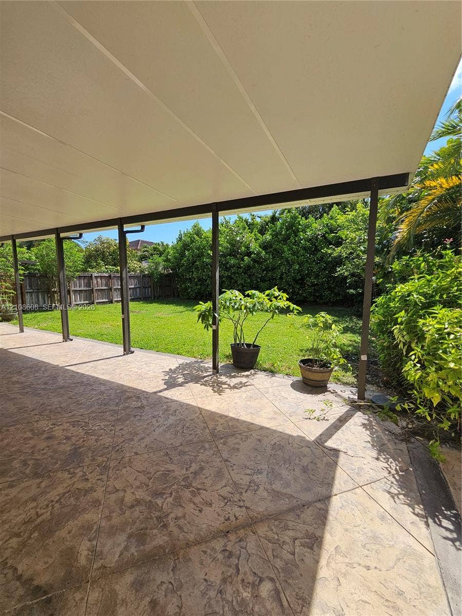 24041 SW 114th Place, Homestead, FL 33032 Covered patio with stamped concrete flooring, grass lawn, and perimeter wood fencing