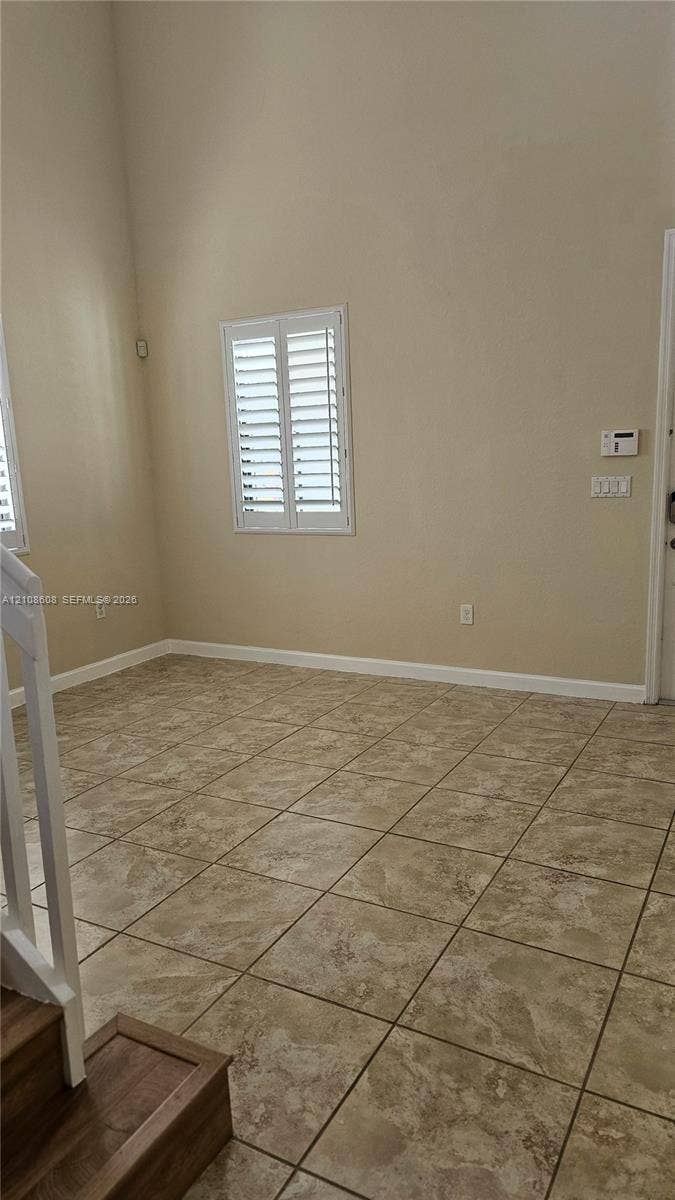 24041 SW 114th Place, Homestead, FL 33032 High-ceiling interior featuring tiled flooring, plantation shutters, and a wood-finish staircase railing