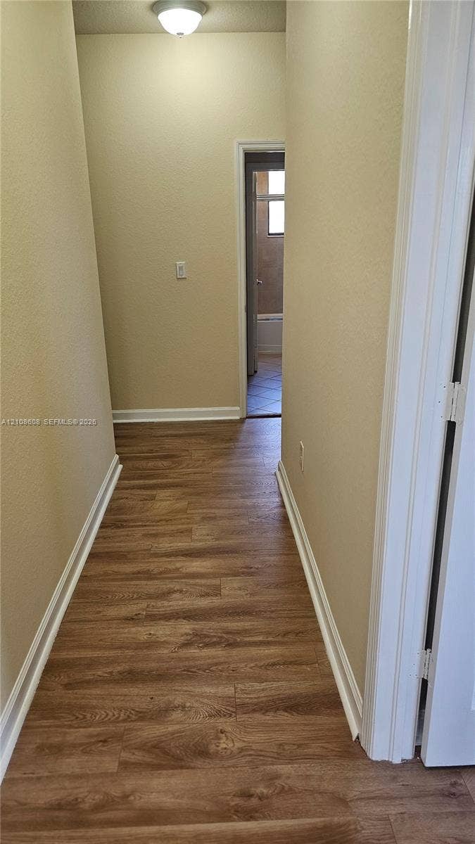 24041 SW 114th Place, Homestead, FL 33032 Hallway featuring wood-finish flooring, neutral-toned walls, and a flush-mount ceiling light fixture