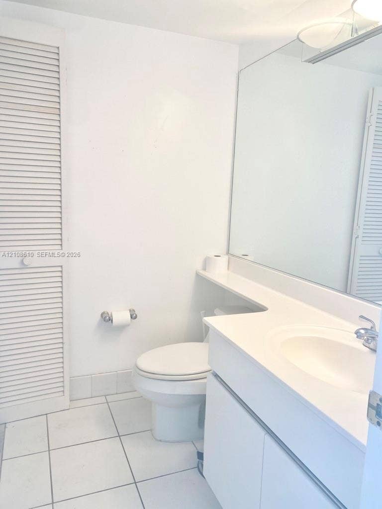 1900 Sunset Harbour Drive, #1210, Miami Beach, Miami Beach, FL 33139 Bathroom featuring a white vanity cabinet, solid-surface countertop with an integrated sink, full-width vanity mirror, louvered closet doors, and ceramic tile flooring