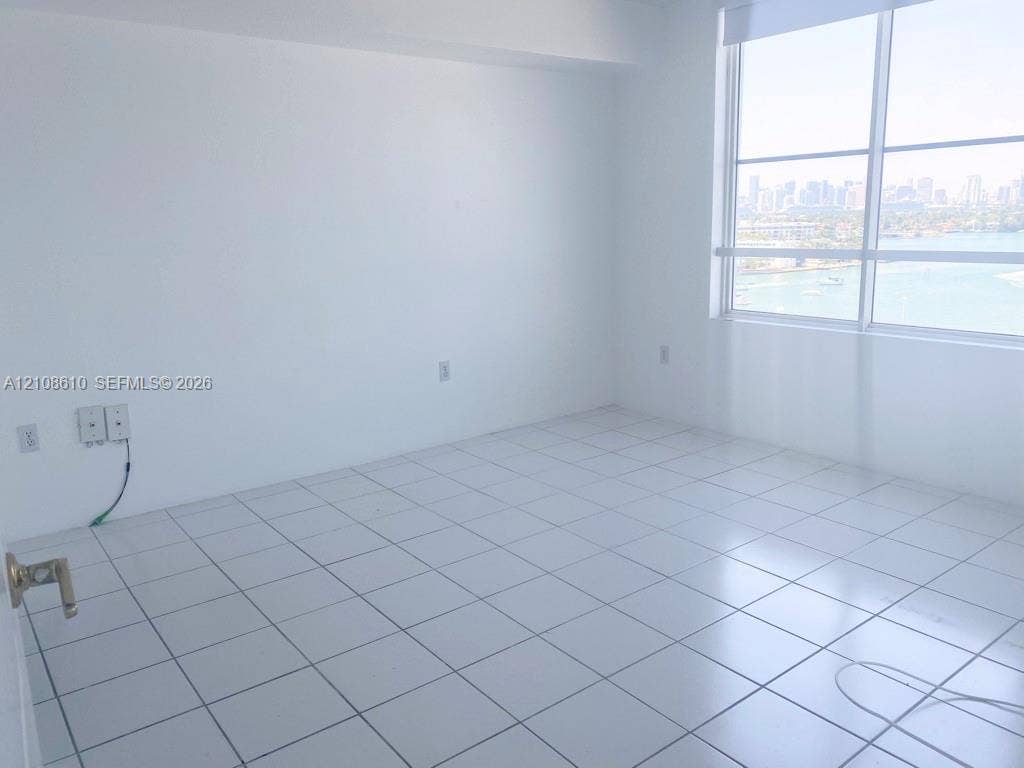 1900 Sunset Harbour Drive, #1210, Miami Beach, Miami Beach, FL 33139 Bright room featuring white ceramic floor tiles, floor-to-ceiling windows, and an expansive cityscape and water horizon