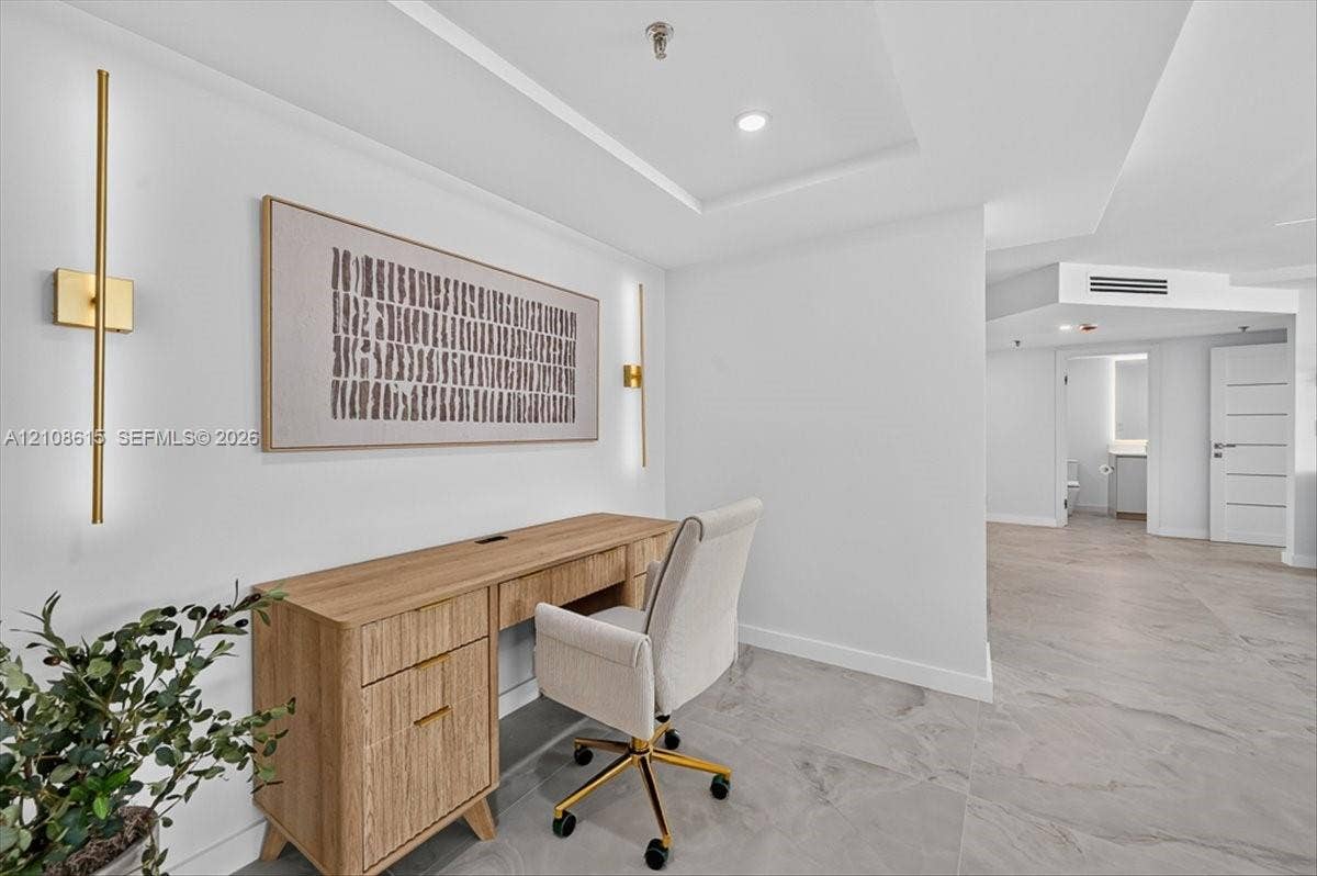 9455 Collins Avenue, #1201, Surfside, FL 33154 Neutral-toned tile flooring, recessed tray ceiling lighting, and dual vertical gold-tone wall sconces