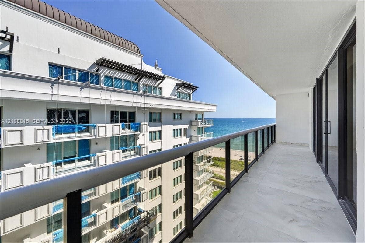 9455 Collins Avenue, #1201, Surfside, FL 33154 Covered balcony featuring large-format stone-finish tile flooring, sleek dark metal railings with glass panels, and sliding glass door access