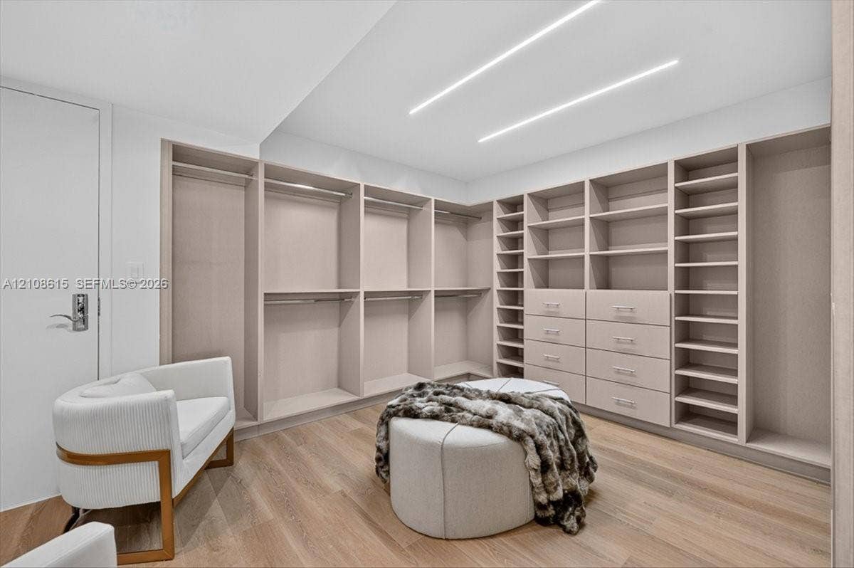 9455 Collins Avenue, #1201, Surfside, FL 33154 Custom reach-in closet featuring light wood-finish shelving, integrated drawers with hardware, wood-finish flooring, and recessed linear ceiling lighting