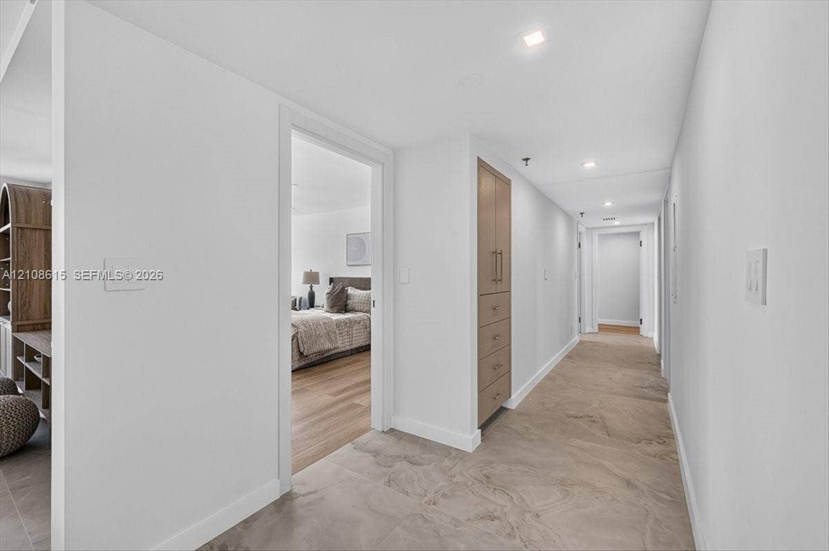 9455 Collins Avenue, #1201, Surfside, FL 33154 Hallway featuring large-format tile flooring, recessed ceiling lighting, and built-in floor-to-ceiling cabinetry with wood-finish doors