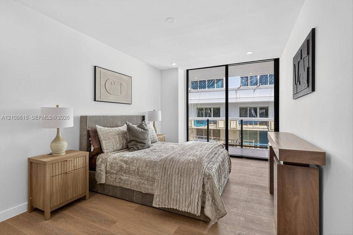 9455 Collins Avenue, #1201, Surfside, FL 33154 Wood-finish flooring, floor-to-ceiling glass sliding door, integrated recessed lighting, and a private balcony with glass railing
