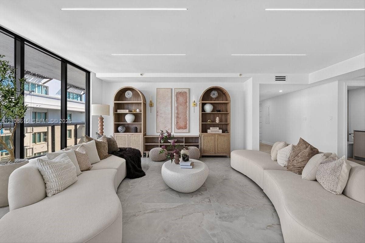 9455 Collins Avenue, #1201, Surfside, FL 33154 Floor-to-ceiling windows with dark framing, custom built-in arched wood shelving, and large-format stone-finish tile flooring