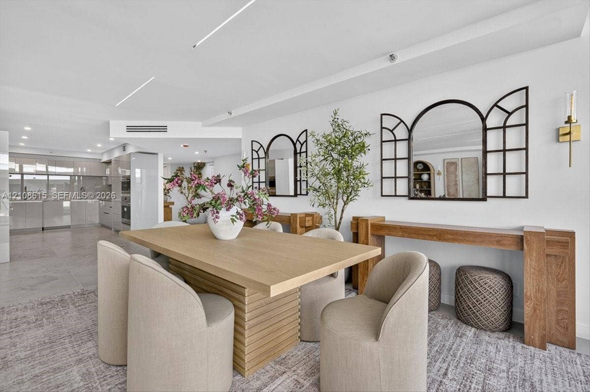 9455 Collins Avenue, #1201, Surfside, FL 33154 Open-concept living space featuring high-gloss cabinetry, linear recessed lighting, stone-finish flooring, and wall-mounted brass light fixtures