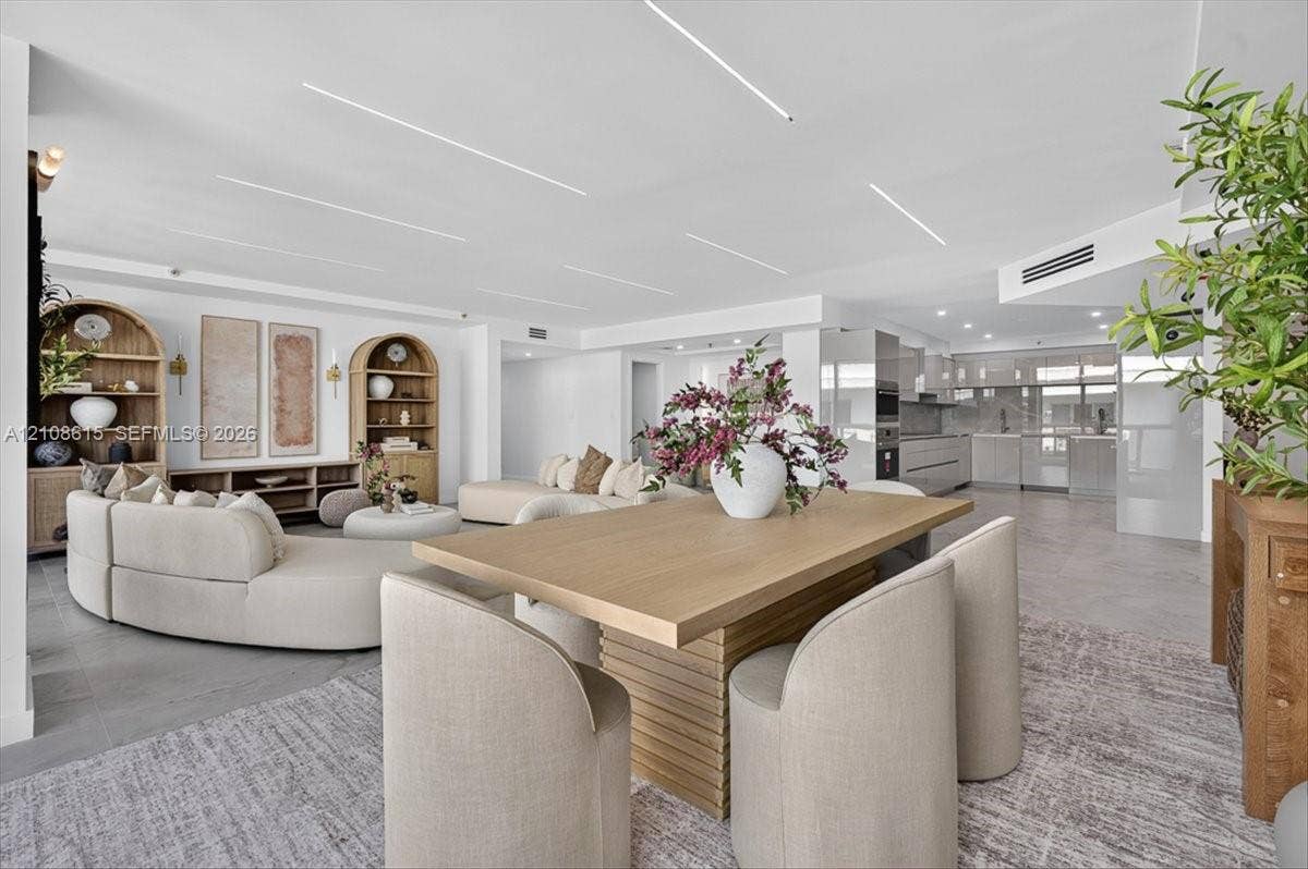 9455 Collins Avenue, #1201, Surfside, FL 33154 Open-concept interior featuring linear recessed ceiling lighting, built-in arched shelving units, neutral large-format tile flooring, and integrated kitchen cabinetry