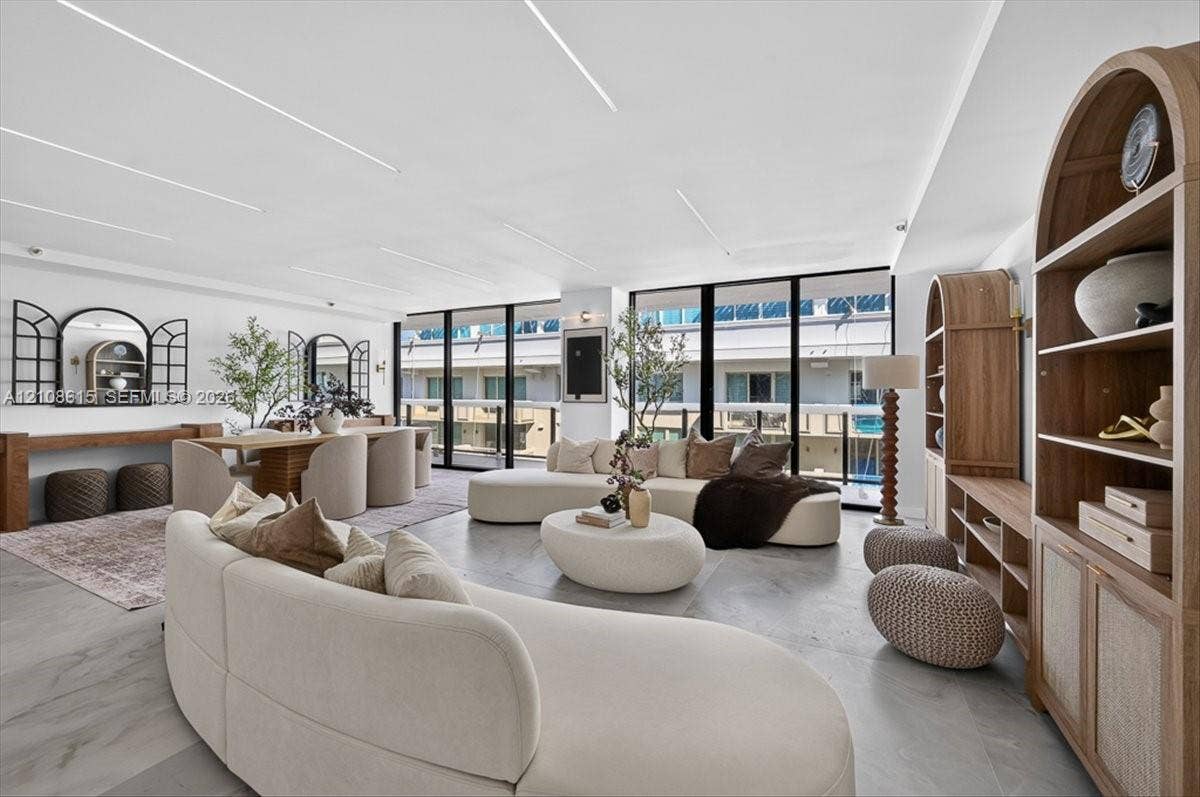 9455 Collins Avenue, #1201, Surfside, FL 33154 Open-concept interior featuring large-format tile flooring, floor-to-ceiling windows, custom built-in arched cabinetry, and recessed linear ceiling lighting