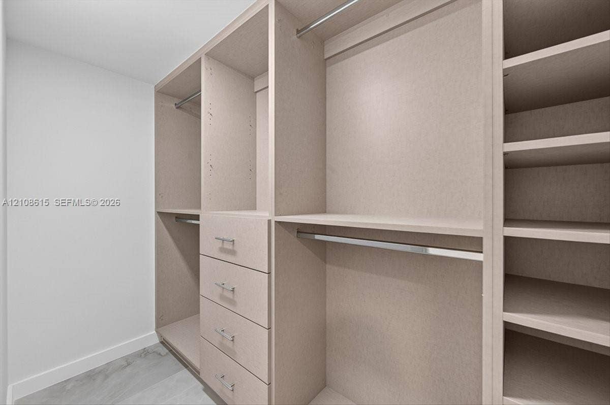 9455 Collins Avenue, #1201, Surfside, FL 33154 Custom reach-in closet featuring light-toned cabinetry, four integrated storage drawers, chrome hardware, multiple shelving tiers, and brushed metal hanging rods